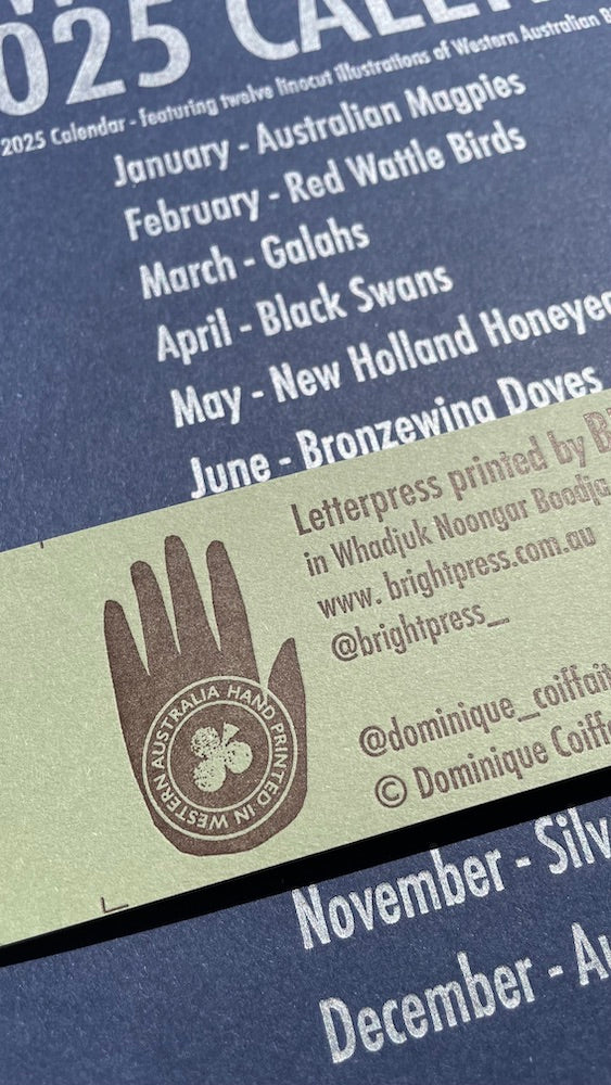 Details of the belly band of 2025 WA Birdlife Calendar featuring an illustration of a hand with text in circular formation reading "hand printed in Western Australia"