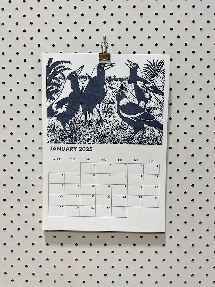 2025 WA Birdlife Calendar with its gold bull-dog clip hanging on a pegboard