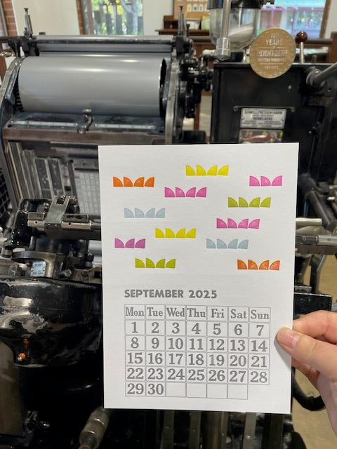 September 2025's page in front of our Heidelberg printing press