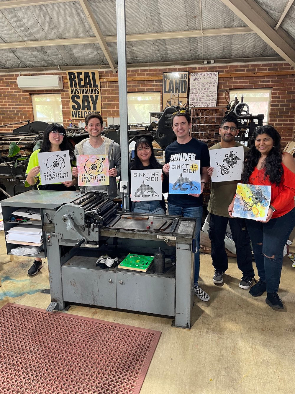 Six participants posing with their prints behind out Vandercook press.