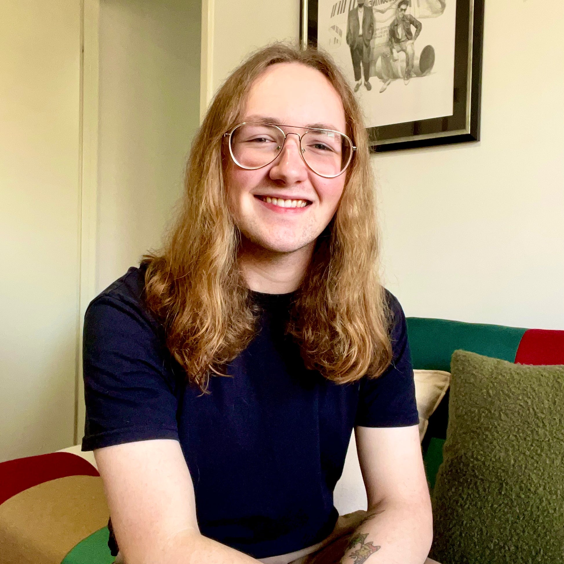 Image of Cassidy North, a smiling man wearing wire frame glasses and has shoulder length hair.