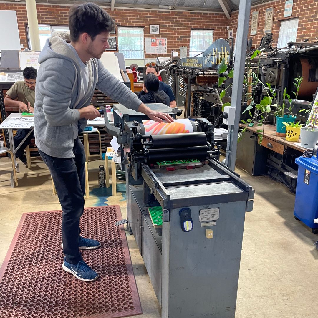 A participant printing their lego tile design on the Vandercook press.