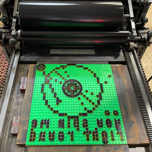 Lego base plate with a lego tiles design inked up on our Vandercook press ready to be printed.